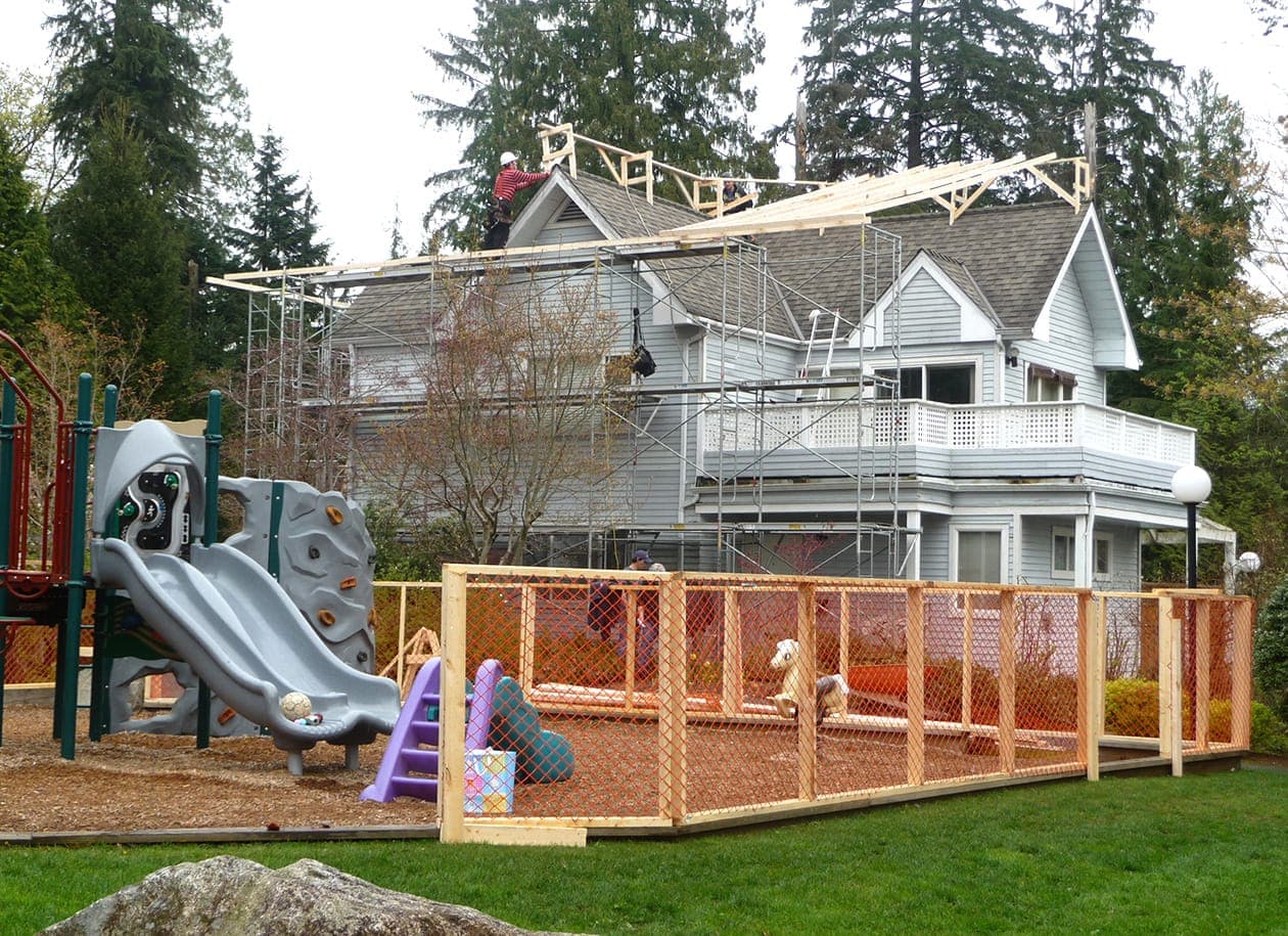Crews on scaffolding rebuilding a roof during the refit, playground fenced off in the foreground